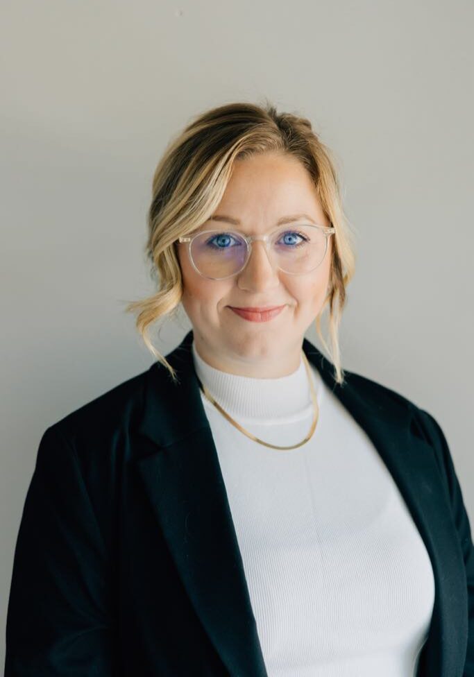 A woman wearing glasses and a black jacket.